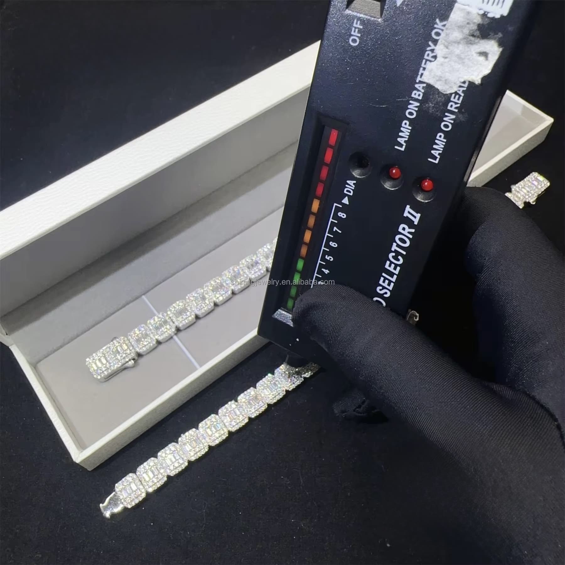 Diamond bracelet being tested with a diamond tester on a black surface

